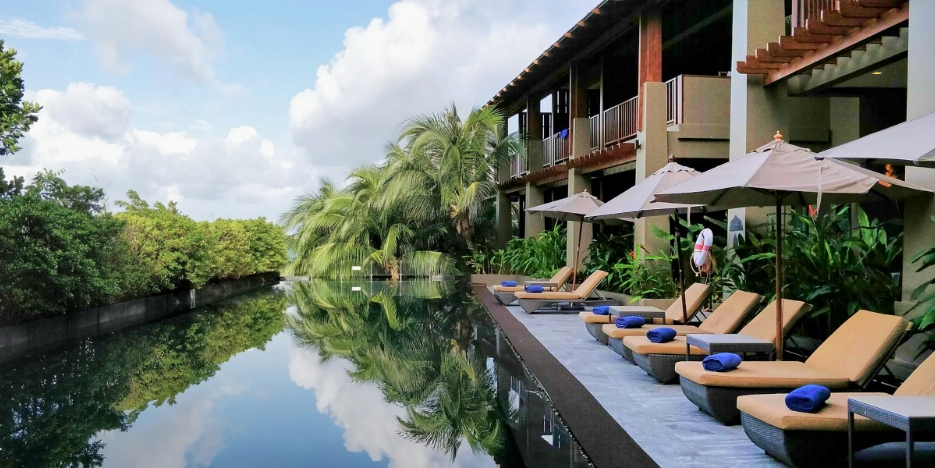 a row of lounge chairs by a pool at a resort.