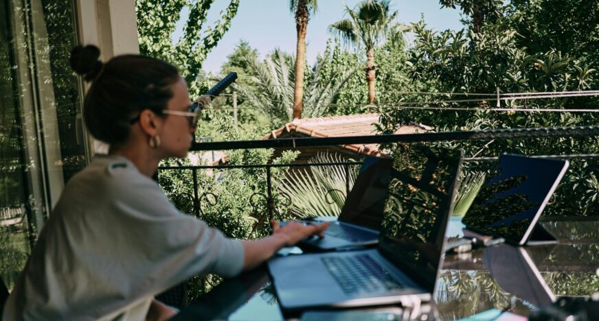 a woman working on two laptops.