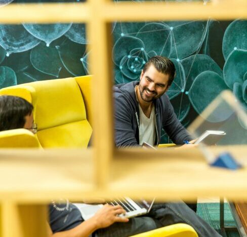 a man sitting down and looking at another man.